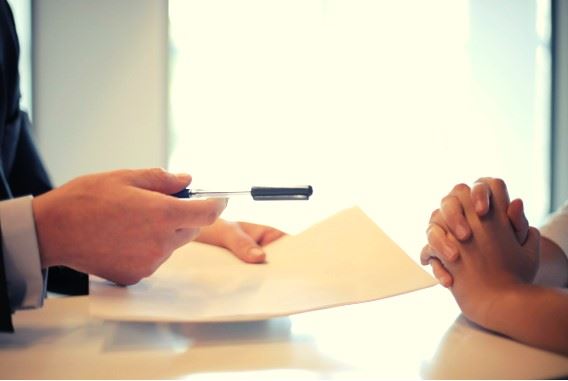 insurance agent offering pen to sign contract