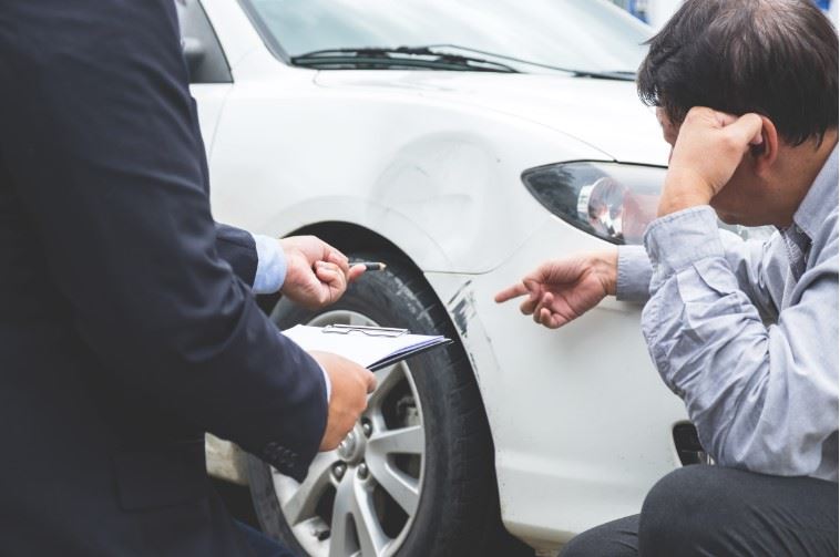 insurance adjuster inspecting car after accident