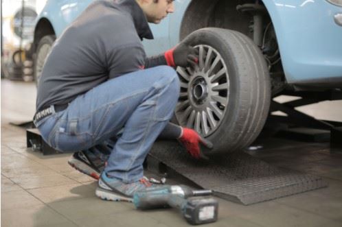 man checking the tire pressure on his car