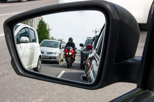 view of motorcyclist lane splitting in rearview mirror