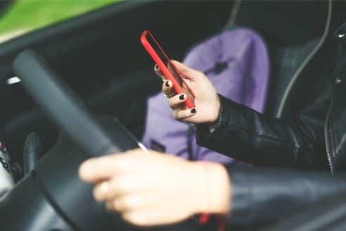 young woman texting while driving her car